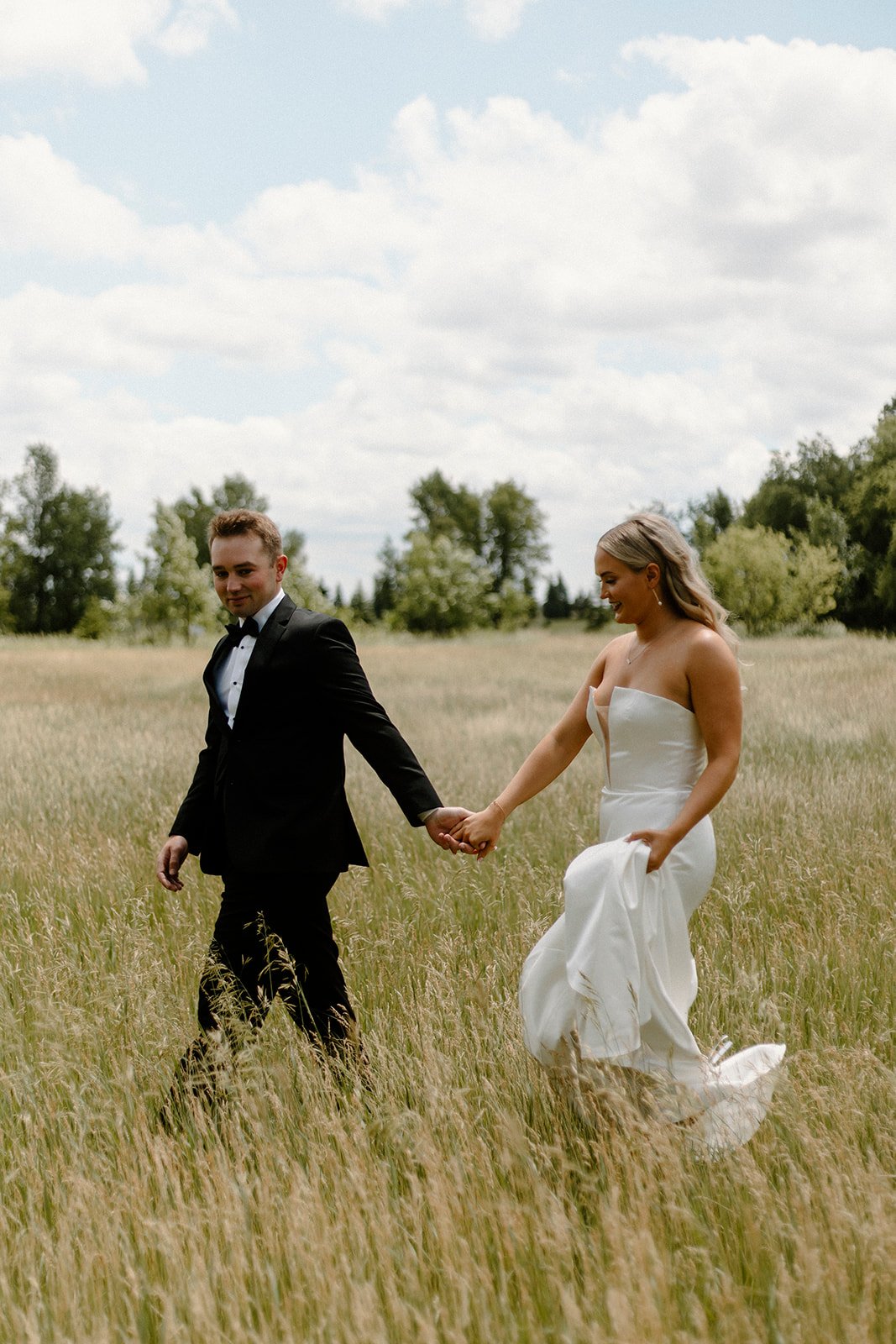 newlywed couple walking hand in hand in a big yellow field